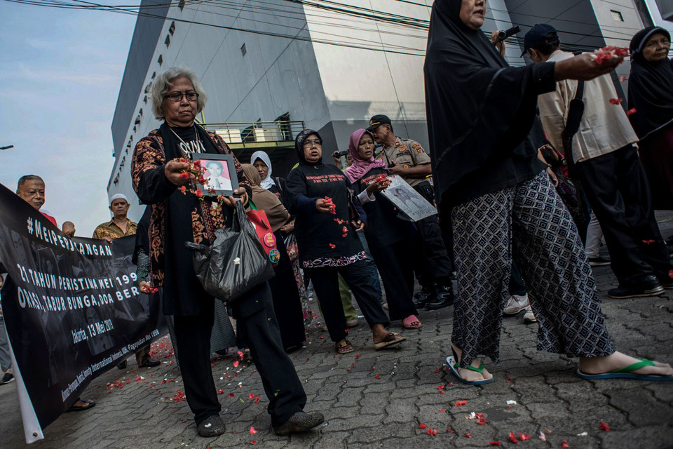 Families and relatives of victims of the May 1998 Jakarta riots scatter flowers at Klender Mall in East Jakarta on Monday. (Antara Photo/Aprillio Akbar)