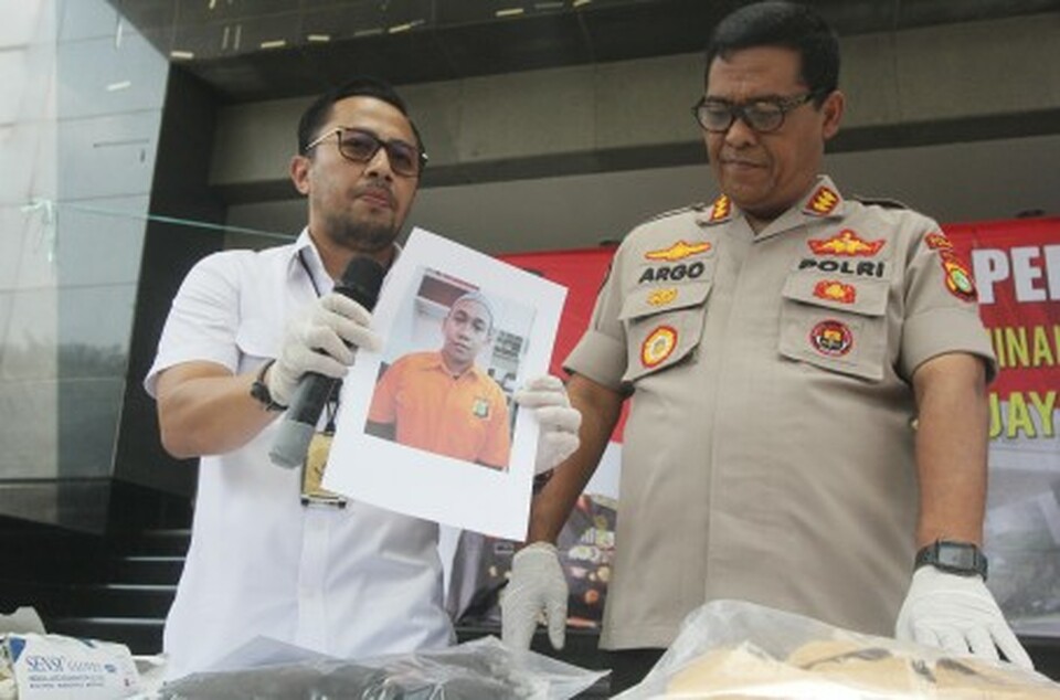 Jakarta Police spokesman Chief Cmr. Argo Yuwono, right, and head of detectives and general crimes unit Dep. Cmr. Ade Indradi show a picture of a man who reportedly threatened to behead President Jokowi in a viral video. (Antara Photo/Reno Esnir)
