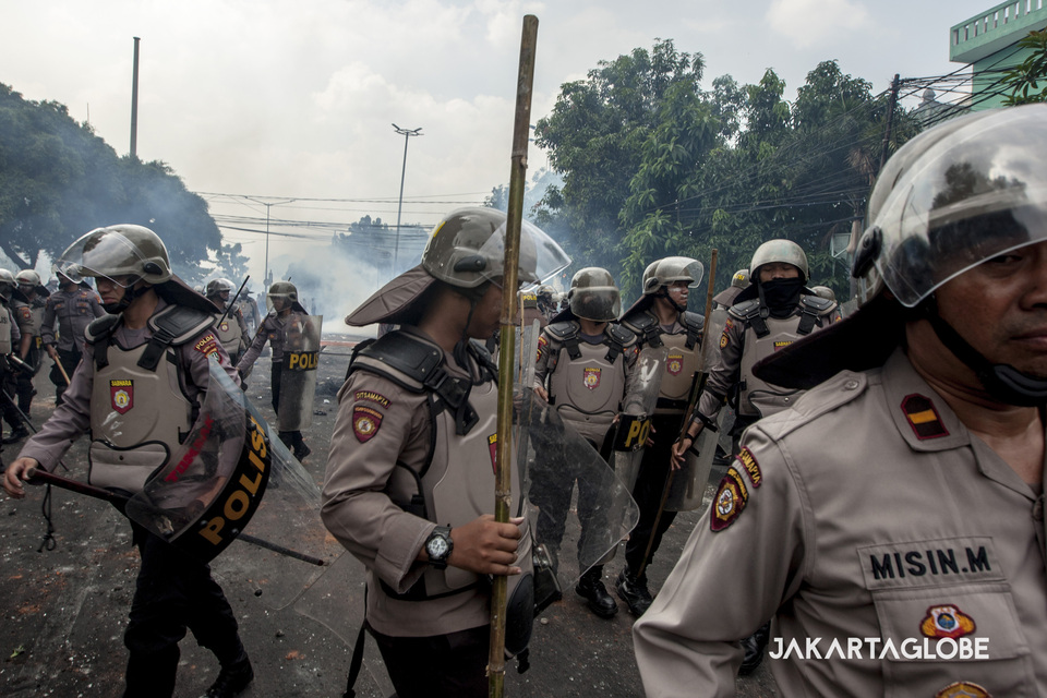 Police fall back after firing tear-gas cannisters into the crowd during rioting in Jalan KS Tubun, Central Jakarta, on Wednesday. (JG Photo/Yudha Baskoro)