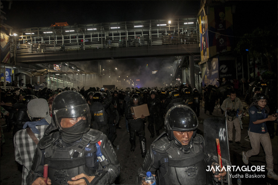 Police officers run away to avoid firecrackers thrown by demonstrators, many of them underage, on Wednesday, May 22. (JG Photo/Yudha Baskoro)