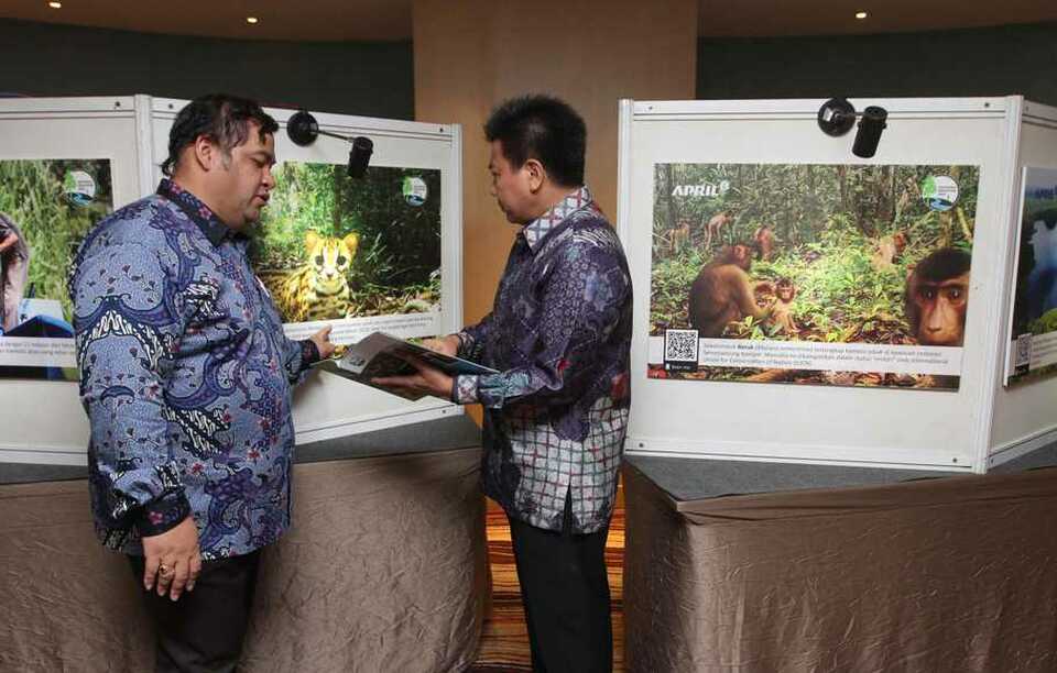 Restorasi Ekosistem Riau external affairs director Nyoman Iswarayoga, left, and president director of Riau Andalan Pulp and Paper Sihol Aritonang observing photos at the RER Annual Report 2018 release event on May 16, in Jakarta. (Photo courtesy of APRIL Group)