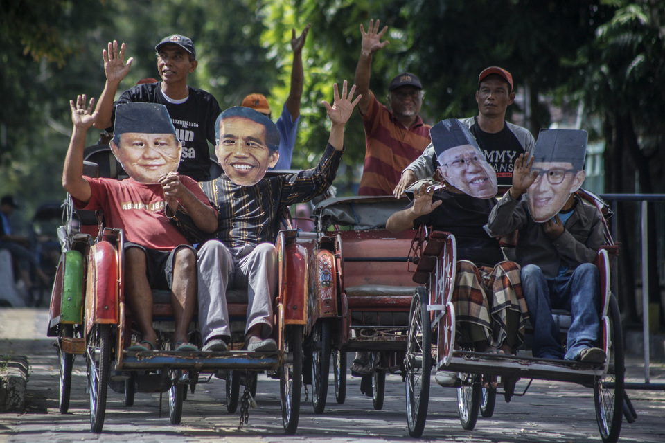 Residents of Solo, Central Java, ride pedicabs while wearing masks of presidential candidate pair Joko 'Jokowi' Widodo and Ma'ruf Amin and challengers Prabowo Subianto and Sandiaga Uno before the April 17 elections. (Antara Photo/Maulana Surya)