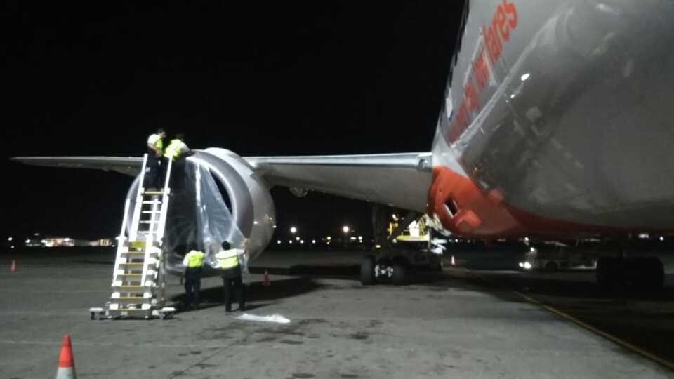 Technicians cover a jet engine at Ngurah Rai International Airport in Bali to protect it from volcanic ash spewed from Mount Agung on Friday evening. (Photo courtesy of Bali airport authority)