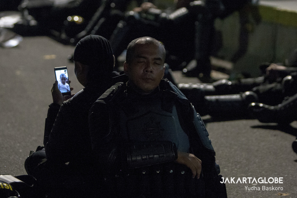 Second Sub-Insp. Rahmat of the National Police's Mobile Brigade Corps (Brimob) photographed while video-calling his child during a lull in the rioting that coincided with the May 22 rally in Central Jakarta. (JG Photo/Yudha Baskoro)