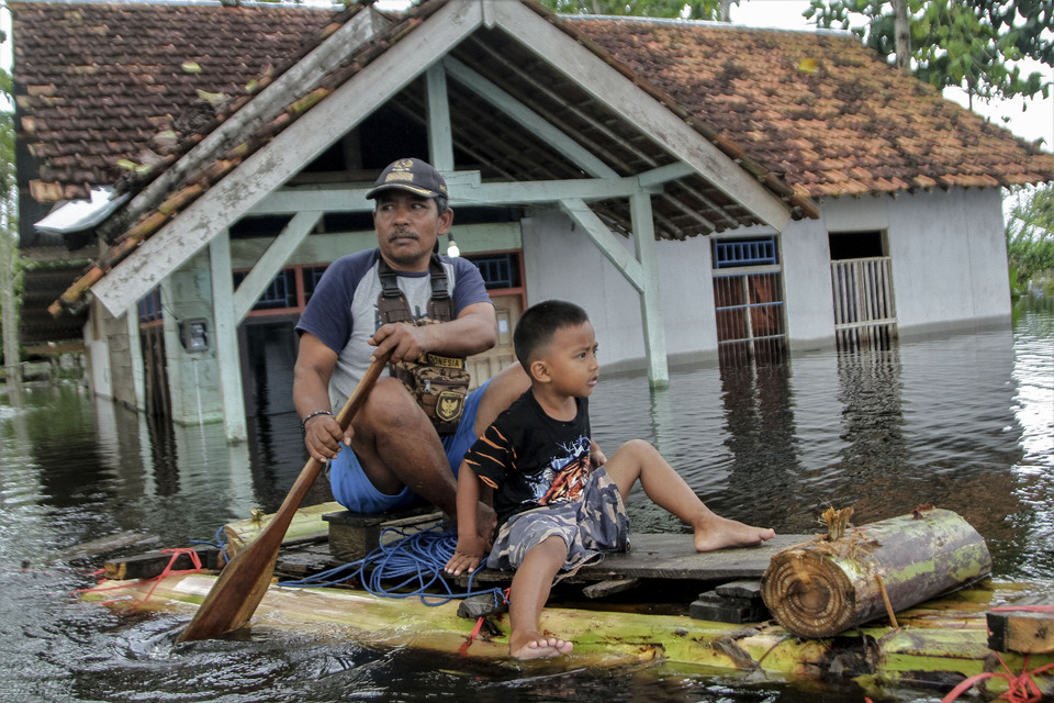 Residents evacuate on a makeshift boat in Laloa, a village near Konawe, Southeast Sulawesi, on Sunday. (Antara Photo/Jojon).