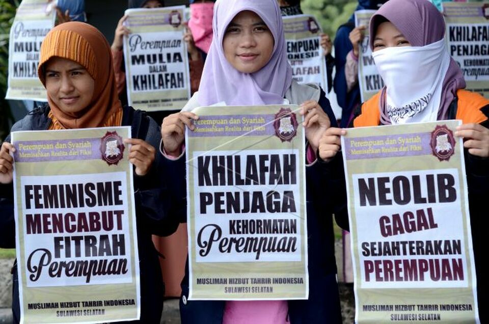 Members of the women's wing of Hizbut Tahrir Indonesia holding up posters during a demonstration in Makassar, South Sulawesi, in 2015. From left, the posters read, 'feminism is not in women's nature,' 'the Caliphate guards the honor of women' and 'neoliberalism has failed to uplift women.' (Antara Photo/Dewi Fajriani)