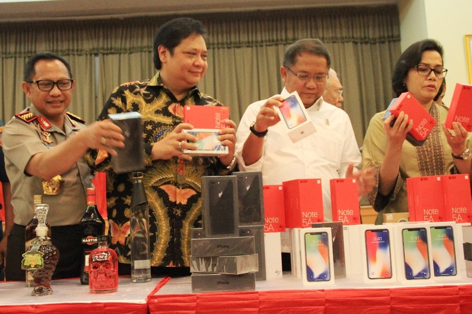 From left, National Police chief Gen. Tito Karnavian, Industry Minister Airlangga Hartanto, Communications Minister Rudiantara and Finance Minister Sri Mulyani Indrawati displaying smuggled alcohol and mobile phones seized by the Directorate General of Customs and Excise in February last year. (Photo courtesy of the Cabinet Secretariat)
