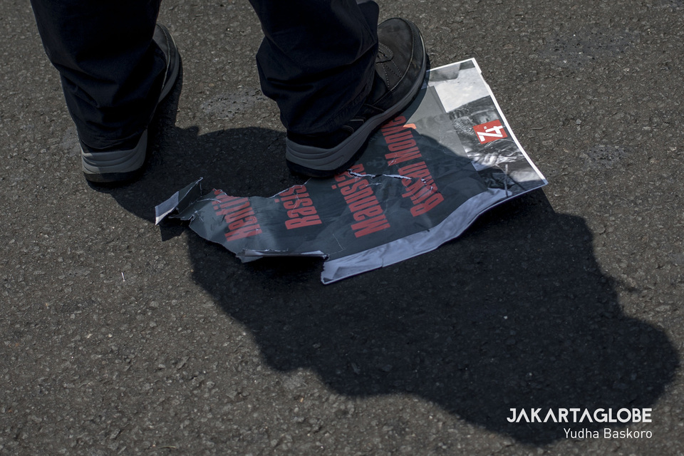 A protester steps on a poster that says 'Stop Racism, We Are Not Monkeys' in Jakarta on Thursday. (JG Photo/Yudha Baskoro)