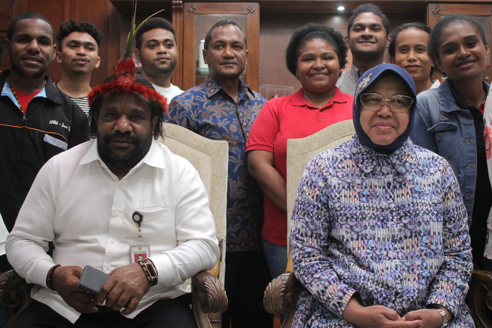 Surabaya Mayor Tri Rismaharini, right, and Lenis Kogoya, special presidential staffer for Papua, pose for a photo with Papuan students in the East Java capital on Tuesday. (Antara Photo/Didik Suhartono)
