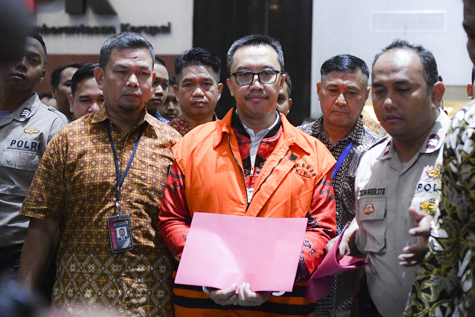 Former sports minister Imam Nahrawi, center, appears in handcuffs and wearing a detainee vest after his interrogation at the Corruption Eradication Commission after in Jakarta on Friday. (Antara Photo/Nova Wahyudi)