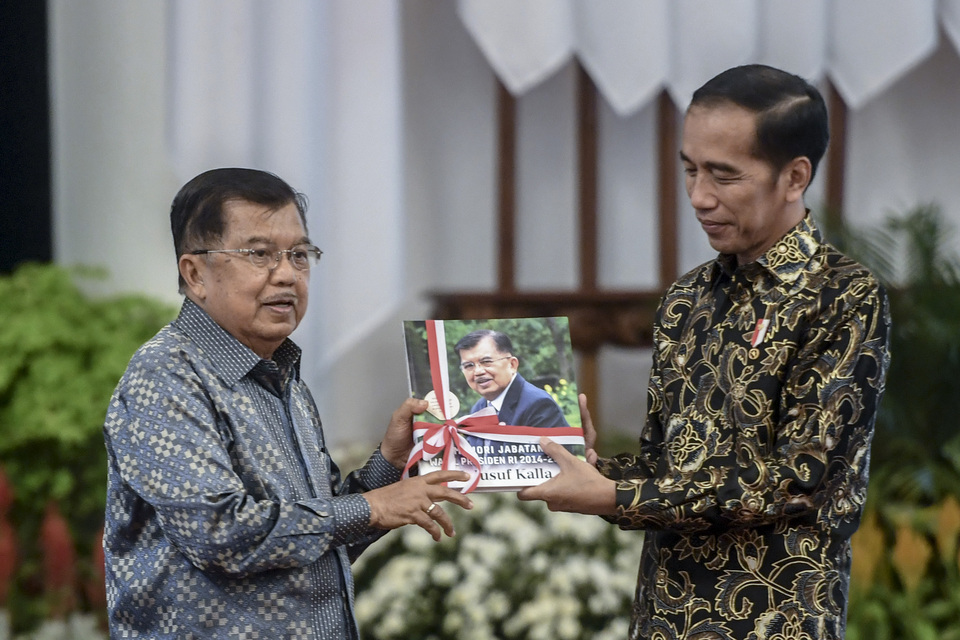 FILE - President Joko Widodo gives a book to Vice President Jusuf Kalla during a cabinet meeting at the State Palace in Central Jakarta on Oct. 18, 2019. (Antara Photo/Akbar Nugroho Gumay)