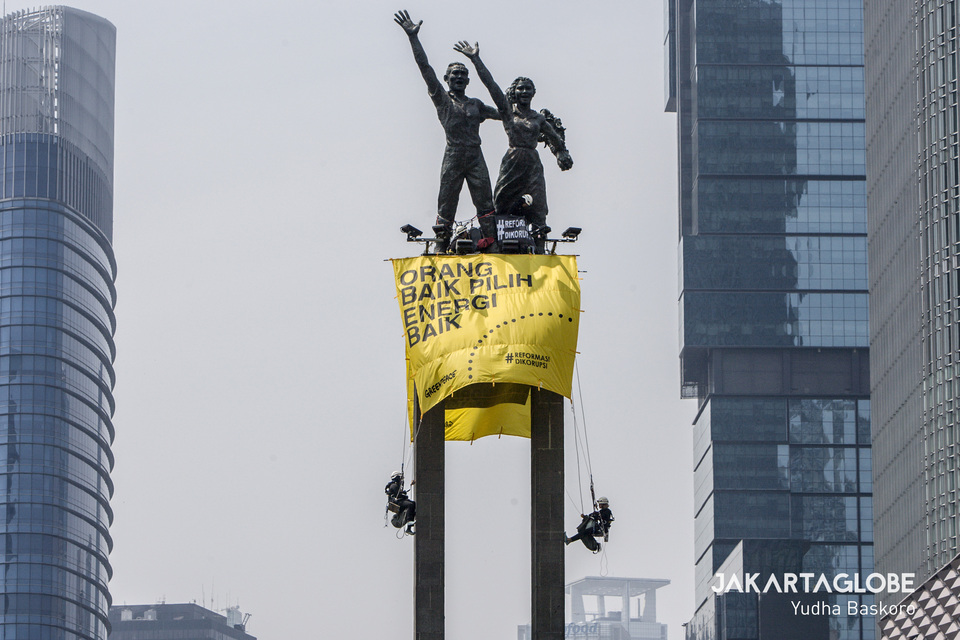Greenpeace activists climb the Selamat Datang statue in Central Jakarta to install two huge banners on Wednesday morning. (JG Photo/Yudha Baskoro)