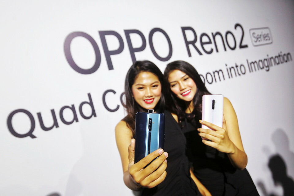 Two models show the latest Oppo smartphones during a launch event in Jakarta in October. (B1 Photo/Ruht Semiono)