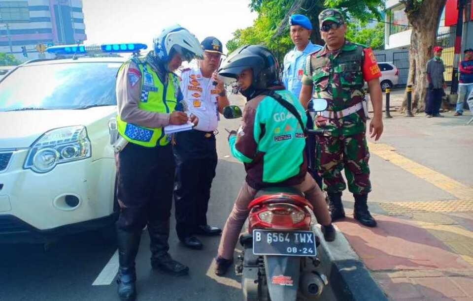 A motorcyclist is issued a police ticket for trespassing a bicycle lane in Jakarta on Monday. (Photo courtesy of the Jakarta Transportation Department)
