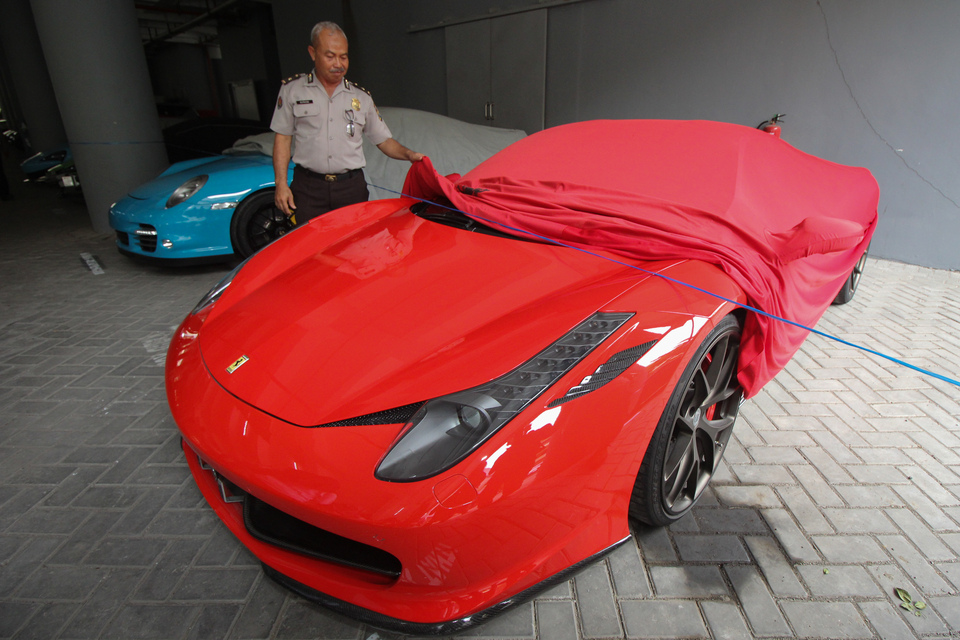 An East Java policeman takes the cover from a Ferrari, which is being kept in custody for tax issues in Surabaya on Monday. (Antara Photo/Didik Suhartono)