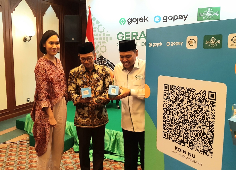 GoPay spokeswoman Winny Triswandhani, left, and the head of NU's philanthropic arm NU Care-Lazisnu, Achmad Sudrajat, right, show off a charity box printed with the QRIS code. (JG Photo/Diana Mariska)