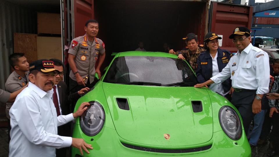 Transportation Minister Budi Karya Sumadi, far right, Finance Minister Sri Mulyani Indrawati, second from right, Attorney General Sanitiar Burhanuddin, second from left, and Police Chief Idham Aziz, fourth from left, pose for a photo around a smuggled Porsche at the Tanjung Priok Port in North Jakarta on Tuesday. (B1 Photo/Carlos Roy Fajarta) 