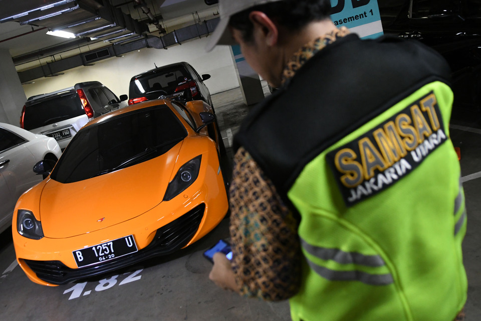 A Jakarta Police officer checks the tax documents of a luxury car parked in a North Jakarta apartment on Dec. 5, 2019. (Antara Photo/M Risyal Hidaya)