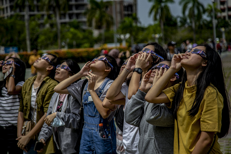 Tourists see the annular solar eclipse using solar glasses in Batam, Riau Islands, Wednesday (26/12). (Antara Photo/M N Kanwa)