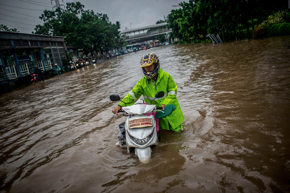 A resident pushes his scooter on Jalan D.I. Panjaitan in Cawang, Jakarta, on Wednesday. (Antara Photo/Aprilio Akbar)