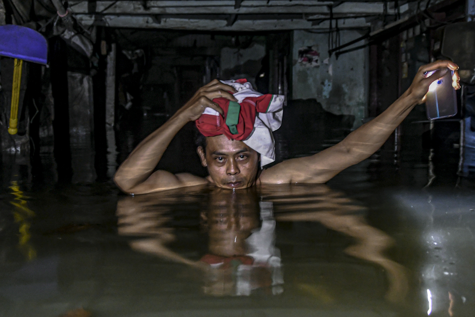 A resident escapes from his home in Kampung Baru near Kembangan, West Jakarta, on Thursday. (Antara Photo/Muhammad Adimaja)