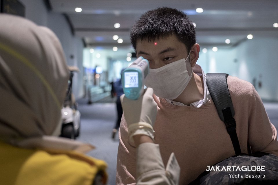 A health inspector points a temperature gun to a passenger at Soekarno-Hatta International Airport in Tangerang, Banten, on Tuesday. (JG Photo/Yudha Baskoro)