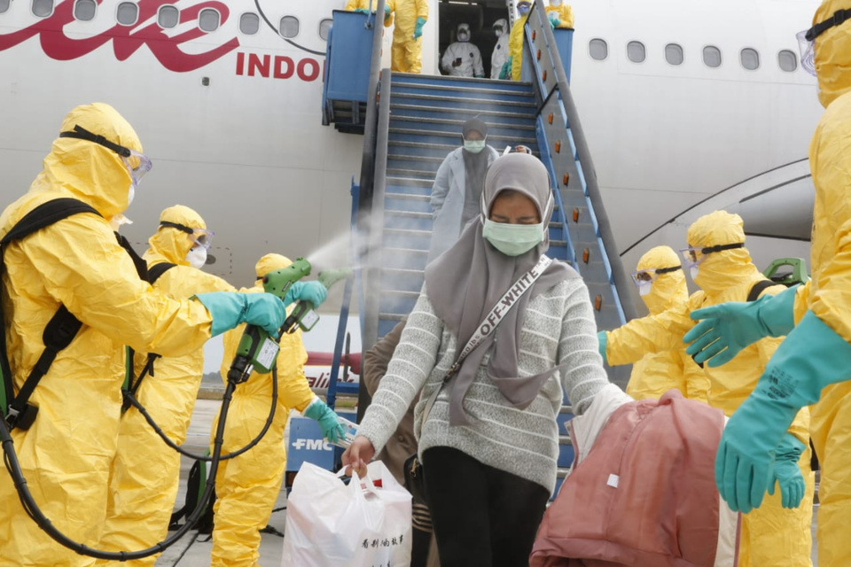 Medical staffs spray disinfectant at Indonesian passengers arriving from the Chinese city of Wuhan at the Hang Nadim Airport on Batam Island. The plane carrying the evacuees lands on the island on Sunday morning. (Antara Photo)