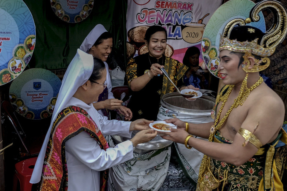 A woman offers sweet porridge to a man dressed up as a wayang character at Ndalem Djojokusuman in Solo, Central Java, on Monday. (Antara Photo/Maulana Surya)