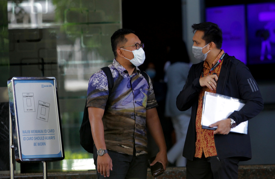 Two employees wearing surgical mask exit BRI 2 Tower in South Jakarta on Jan. 23, when an unsubstantiated rumor about a novel coronavirus victim working there causes panic in the building. (Antara Photo/Reno Esnir)