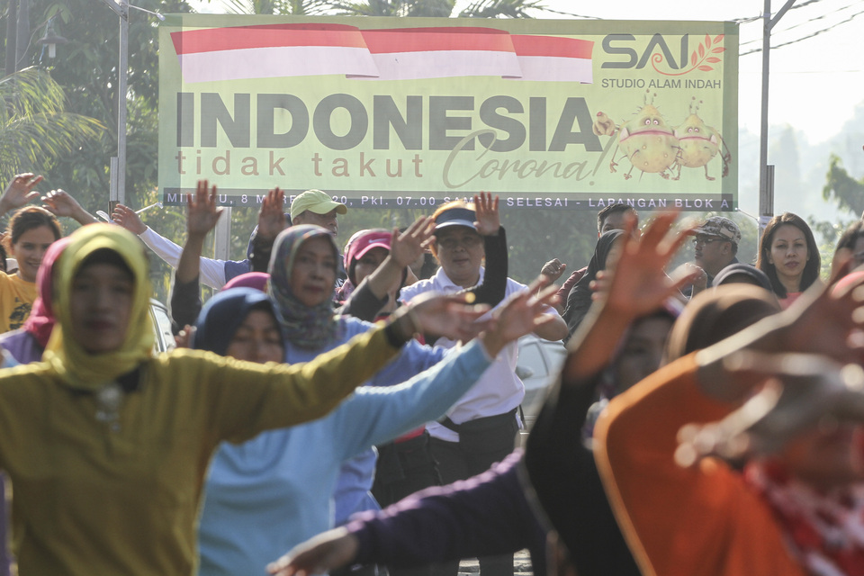 Residents at a housing complex in Depok, West Java, do exercise on Sunday, after two women in the complex tested positive for coronavirus. The banner on the background reads “Indonesia is not afraid of coronavirus”. (Antara Photo /Asprilla Dwi Adha)