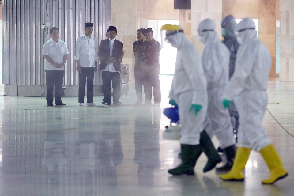 Health workers spray disinfectant inside the Istiqlal Mosque in Jakarta on March 13, as President Joko Widodo, second from left, looks on. (Bi photo/Joanito De Saojoao)