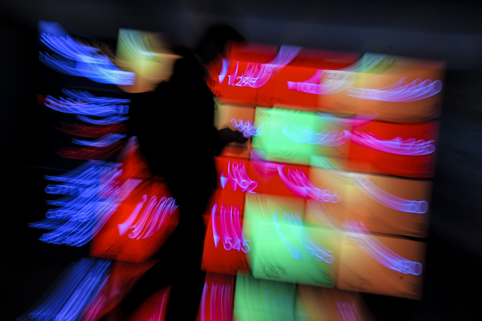 A staff walks in front of a screen that displays stock movements at the Indonesia Stock Exchange in Jakarta on March. (Antara Photo/Galih Pradipta)