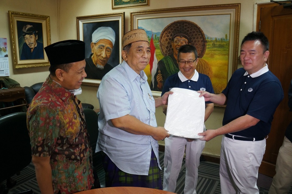 Tzu Chi volunteers and DAAI TV chief executive Hong Tjihn symbolically handed over 100 sets of personal protective equipment to PBNU's Covid-19 officer Syahrizal Syarif in Jakarta on Thursday. (Photo courtesy of Kadin)