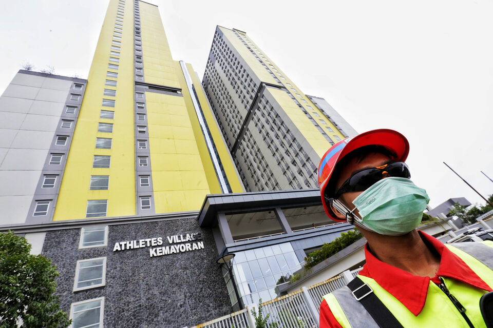 A construction worker wearing surgical mask stands in front of the 2018 Asian Games Village in Kemayoran, Central Jakarta, on Friday. The facility is being renovated as makeshif Covid-19 hospital. (B1 Photo/Ruht Semiono)