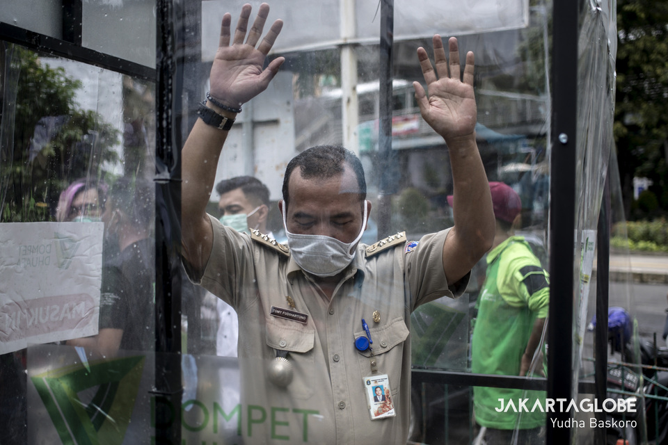 A man walks into a disinfection chamber in front of Blok M Square in South Jakarta on Tuesday. (JG Photo/Yudha Baskoro)