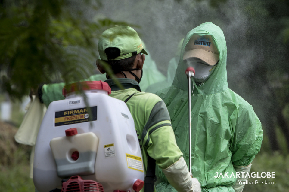 A funeral service worker in protective gear gets sprayed with disinfectant at Tegal Alur cemetery in West Jakarta on March 26. (JG Photo/Yudha Baskoro)