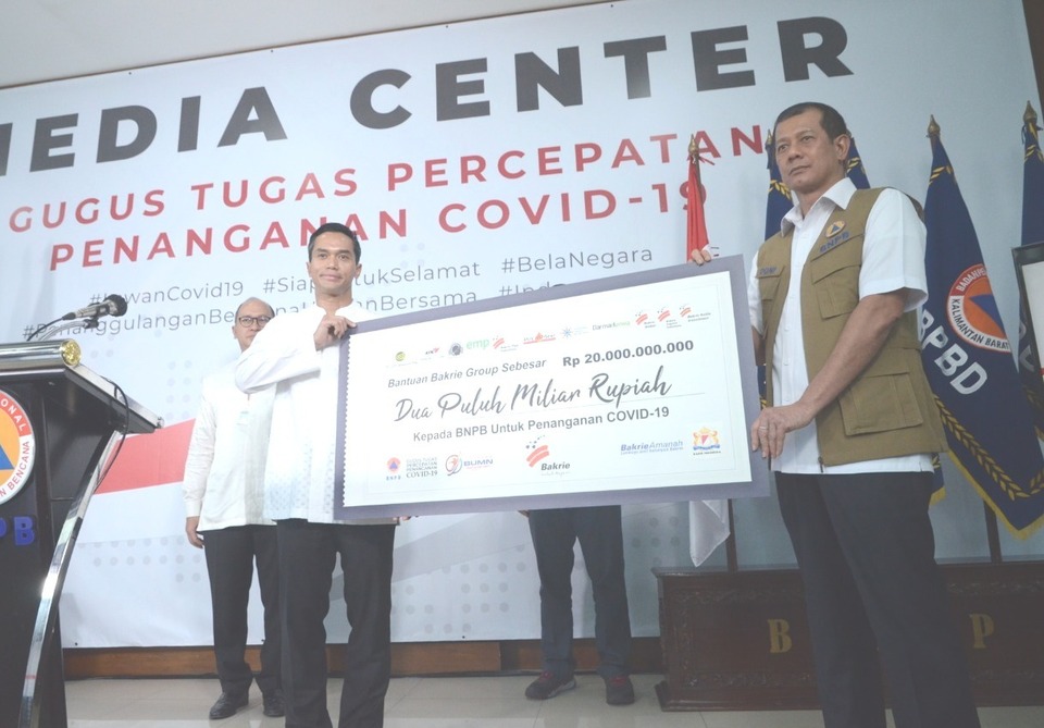 Covid-19 Task Force head Doni Monardo, right, and Bakrie Group chairman Anindya Bakrie hold a placard that simbolically carries a donation of Rp 20 billion for the government's handling of coronavirus outbreak in Jakarta on Friday. (Photo Courtesy of Bakrie Group)