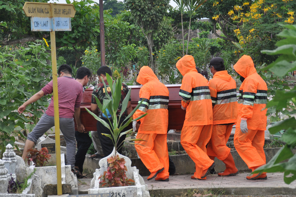 Funeral service workers wearing protective suits carry the coffin of a suspected Covid-19 patient in Medan, North Sumatra, on Monday. The province has reported four deaths from the contagious disease. (Antara Photo/Septianda Perdana)