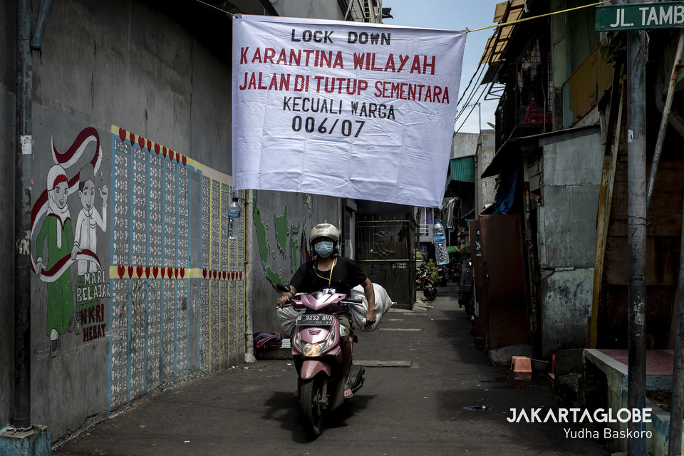 A man rides a motocycle inside a neighborhood in Tambora, West Jakarta, on April 1. The neighborhood has announced a self-imposed lockdown amid Covid-19 fears. (JG Photo/Yudha Baskoro)