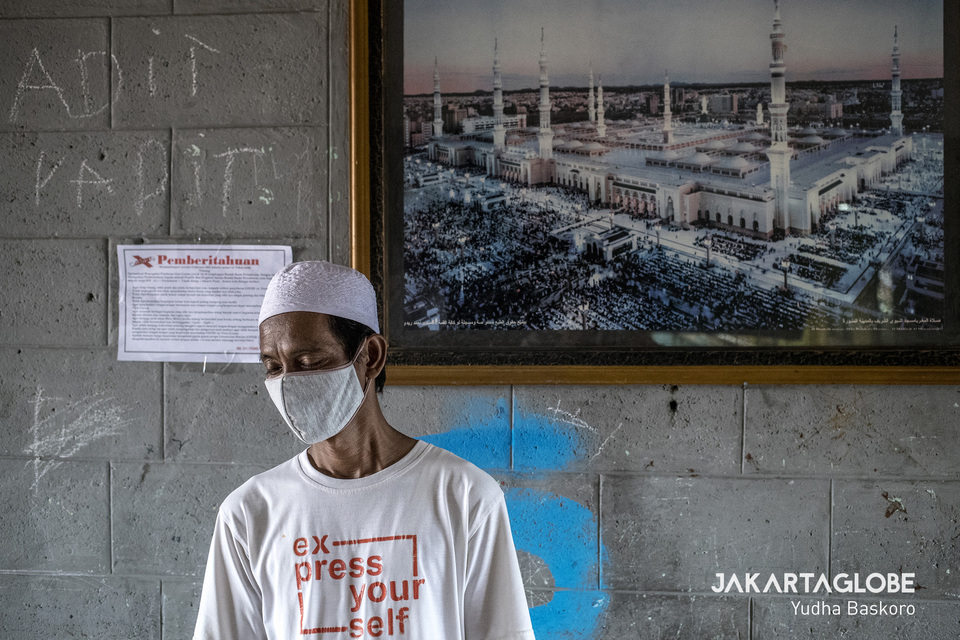 A man wearing a surgical mask stands in front of a picture of the Al-Masjid an-Nabawi mosque in Medina at the Benhil II apartment complex in Central Jakarta on Saturday. (JG Photo/Yudha Baskoro)