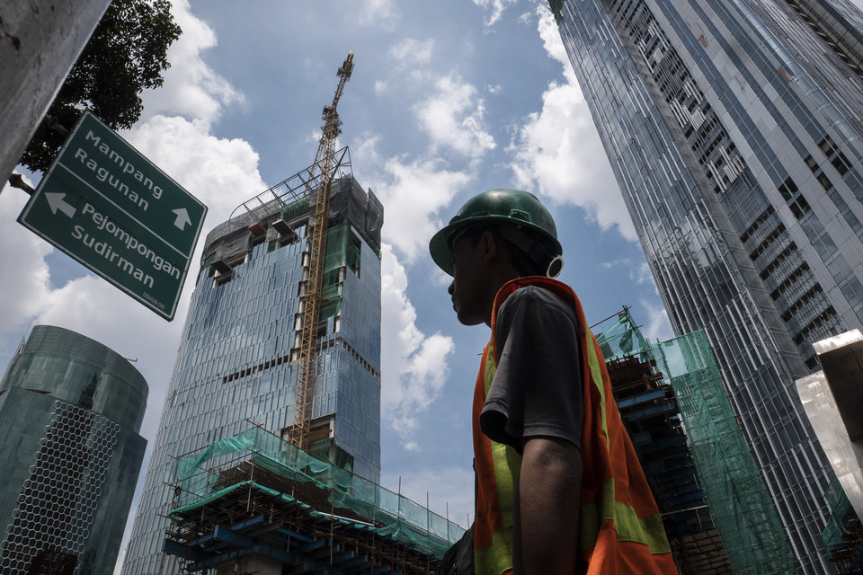 A construction worker walks past a skyscraper under construction in Kuningan, South Jakarta, last week. (Antara Photo/Dhemas Reviyanto)