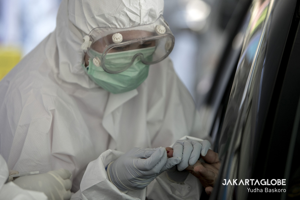 A health worker takes a blood sample through a car window during a drive-through test for Covid-19 at Pajajaran Stadium in Bogor, West Java, on Tuesday. (JG Photo/Yudha Baskoro)