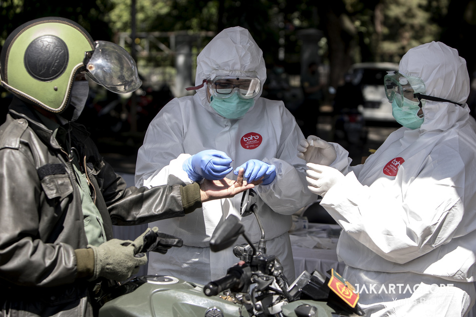 Two medical workers take blood sample from a motorist during a rapid coronavirus testing near Padjadjaran Stadium in Bogor, West Java, on April 7. (JG Photo/Yudha Baskoro)