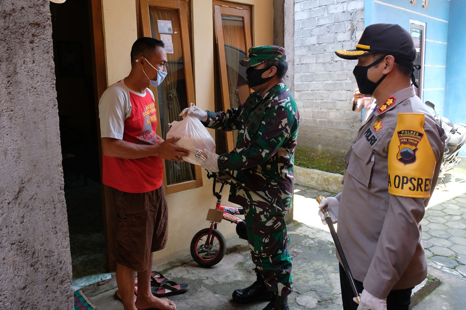 An Army soldier and a police officer deliver food aid to a villager in Temanggung, Central Java, on Thursday. (Antara Photo/Anis Efizudin)
