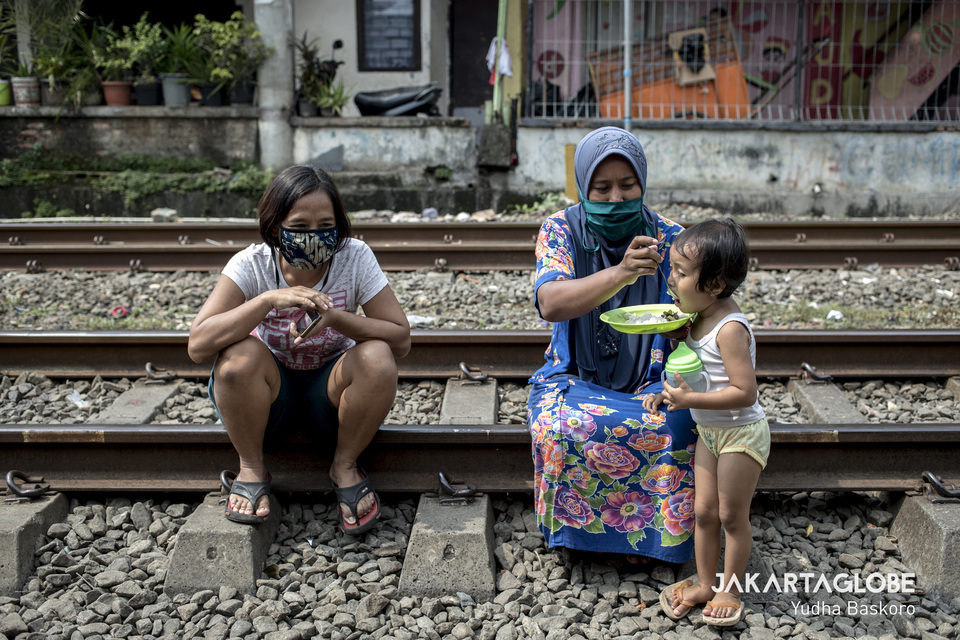 A woman feeds a child on a railway track in Petamburan, Central Jakarta, on April 10, 2020, when the city begins imposing social restrictions amid the Covid-19 outbreak. (JG Photo/Yudha Baskoro)