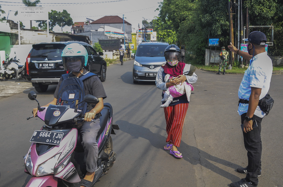 An officer of Bekasi's transportation department stops a motorcycle rider and his passengers at a West Java-Jakarta border in Bekasi, West Java, on Friday. (Antara Photo/Fakhri Hermansyah)