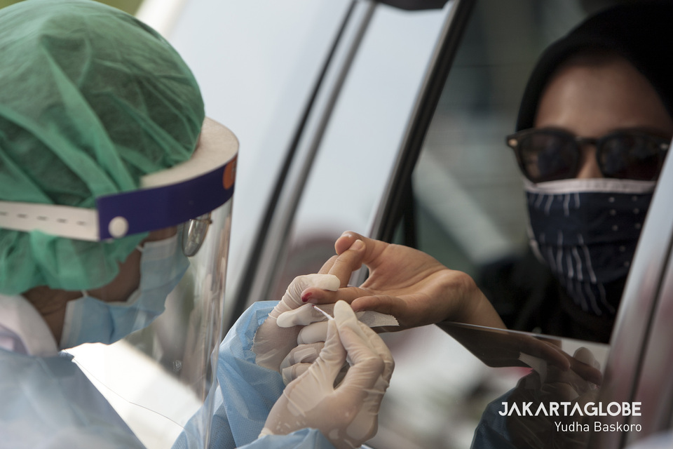 A health worker takes a blood sample from a car driver during a rapid test outside Lippo Mall Puri in West Jakarta on Saturday. (JG Photo/Yudha Baskoro)
