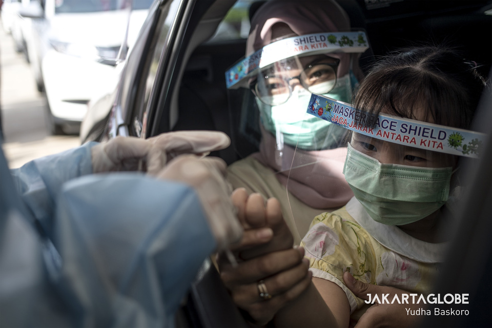 Health workers take a blood sample from a child through the window of a car during a drive-through rapid testing for coronavirus outside Lippo Mall Puri in West Jakarta on April 18. (JG Photo/Yudha Baskoro)