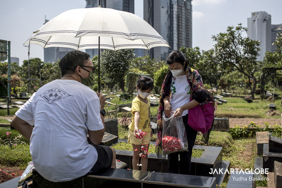 A family visits the grave of a dead relative at Karet Tengsin public cemetery in Central Jakarta on Wednesday. (JG Photo/Yudha Baskoro)