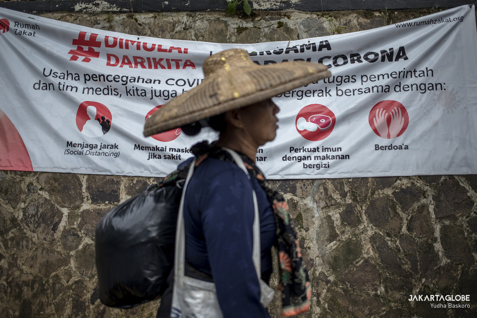 A Baduy woman walks past a Covid-19 mitigation poster near Rangkasbitung, Banten, on April 28. (JG Photo/Yudha Baskoro)